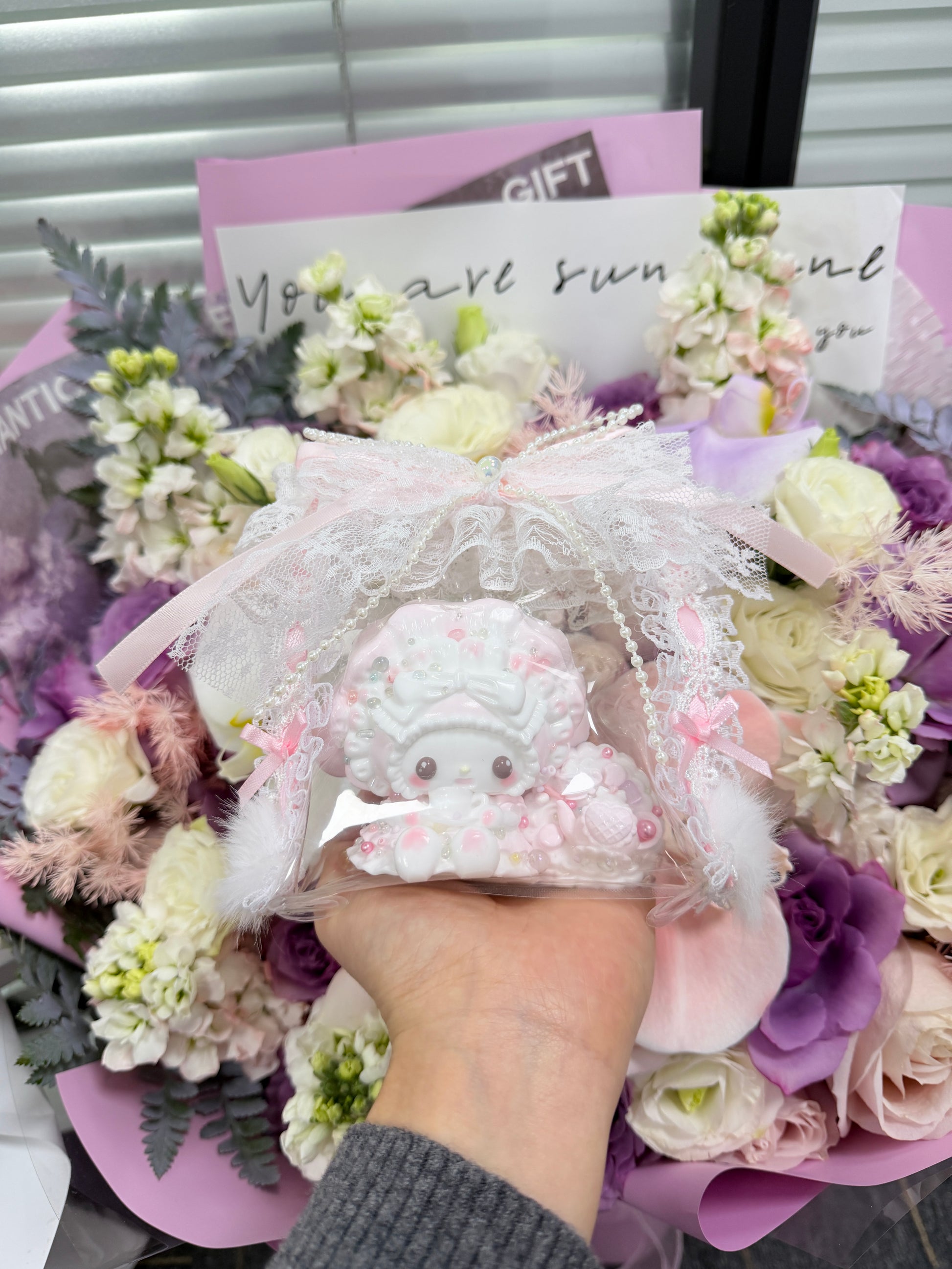 Pink and white kawaii cream bunny squeeze toy with whipped cream swirl texture and colourful bead decorations, packaged in a lace and ribbon gift bag