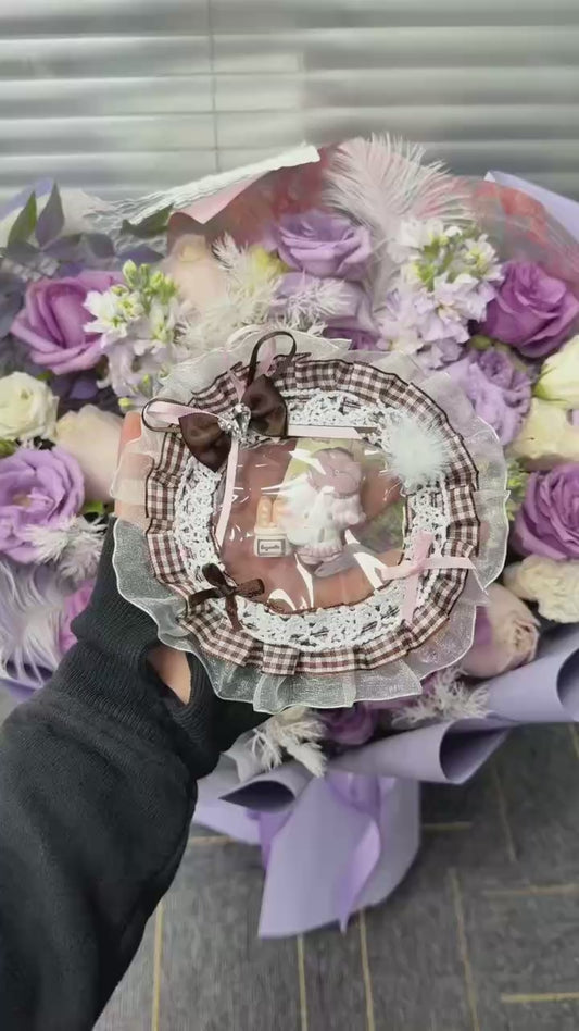 Close-up of food-grade silicone baker lamb squishy showing fluffy white body, lilac four-leaf clover headpiece, and miniature baguette accessory detail