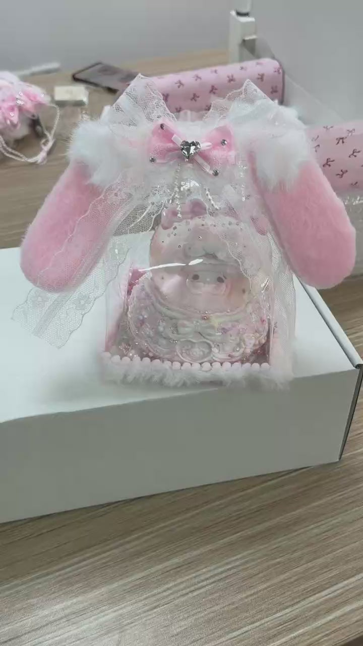 Close-up of food-grade silicone baby pig squishy with pacifier, layered whipped cream body, lace trim, glitter sequins, colourful candy bead decorations, stacked bows, and pearl bead base ring