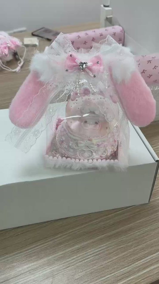 Close-up of food-grade silicone baby pig squishy with pacifier, layered whipped cream body, lace trim, glitter sequins, colourful candy bead decorations, stacked bows, and pearl bead base ring